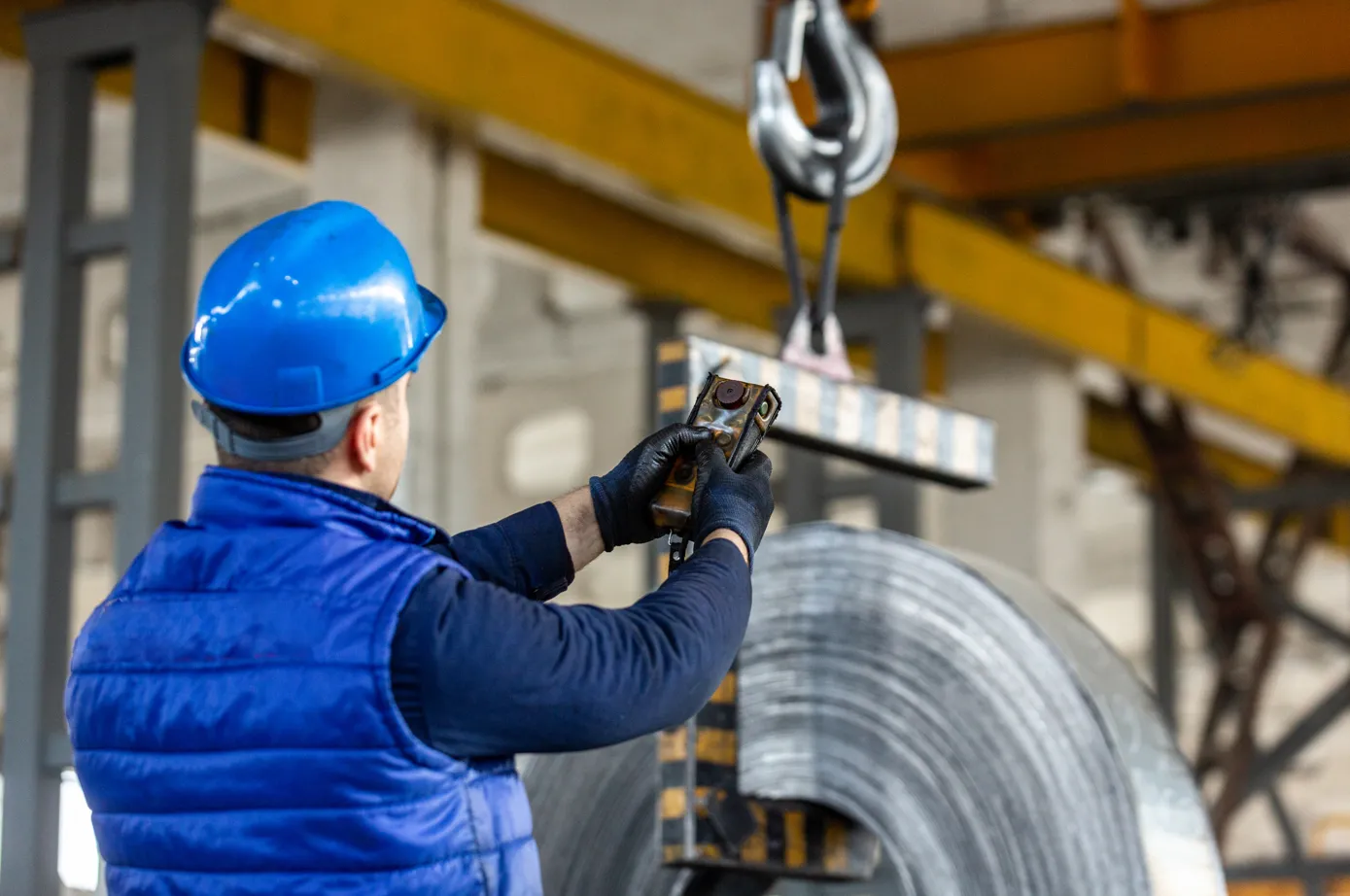 Operatore utilizza carroponte con radiocomando per sollevamento carichi in ambiente industriale