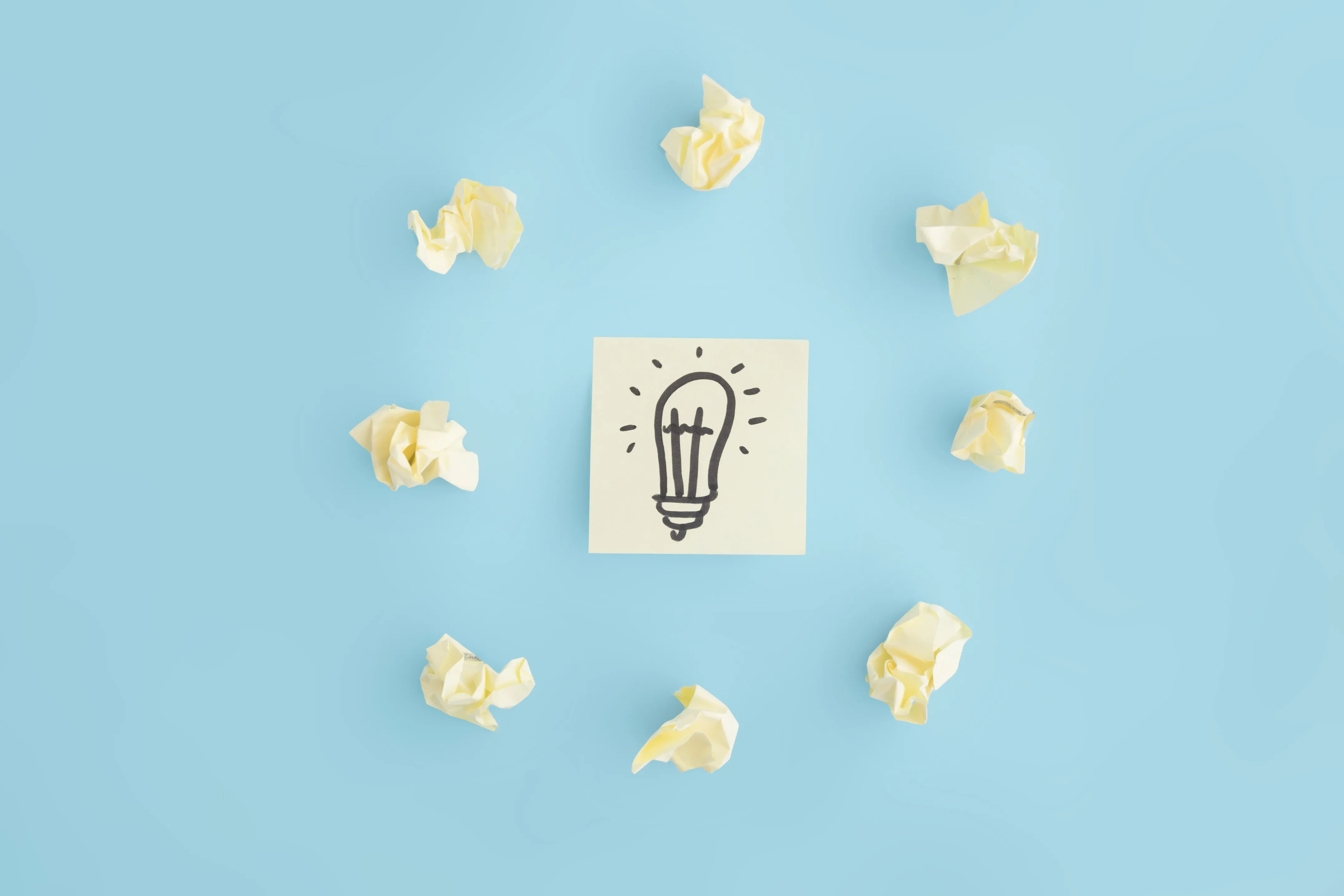 Lampadina disegnata su un foglio circondata da fogli accartocciati, simbolo di problem solving e ricerca di soluzioni